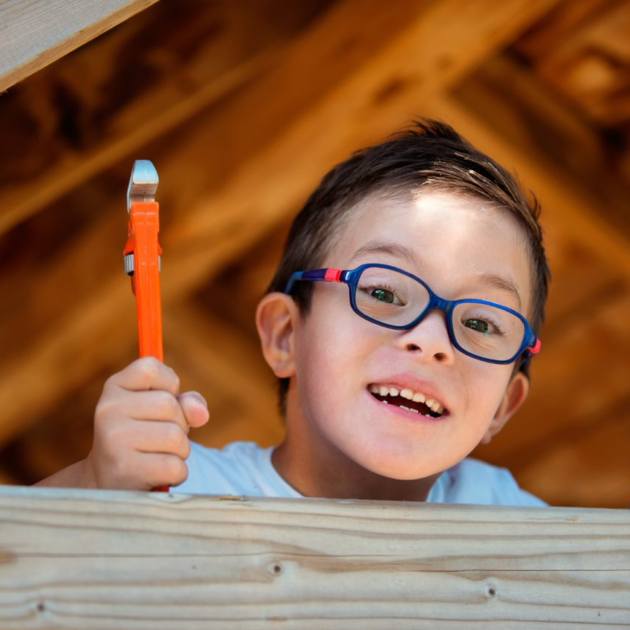 Un niño con gafas que sostiene un pincel.