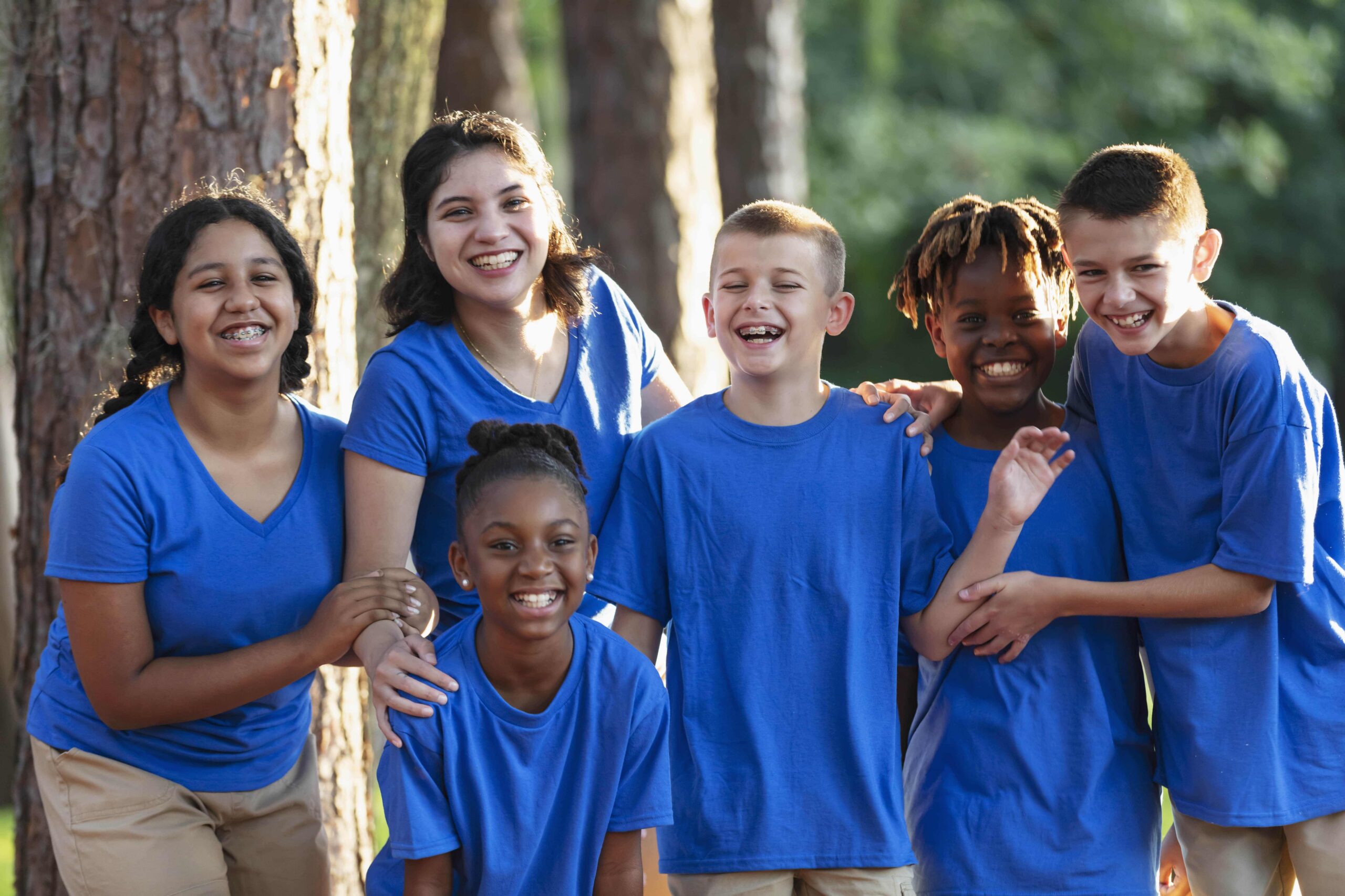 Group of children smiling in blue shirts.