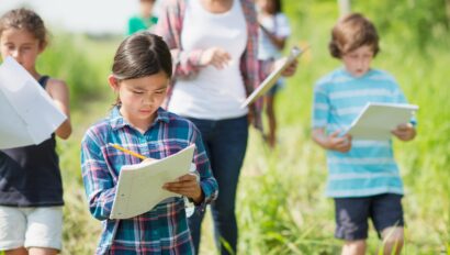 Children and an adult taking notes while exploring outsite.