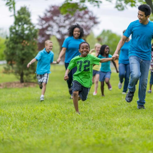 Niños y adultos corriendo y cogidos de la mano.
